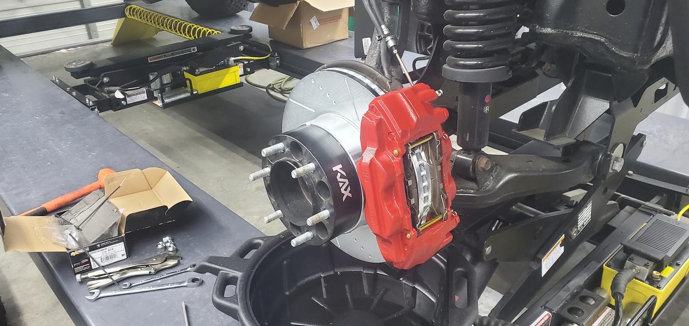 A drilled and slotted brake rotor with a red caliper fitted